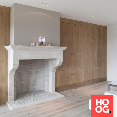 Fireplace in natural stone with oak cupboard wall